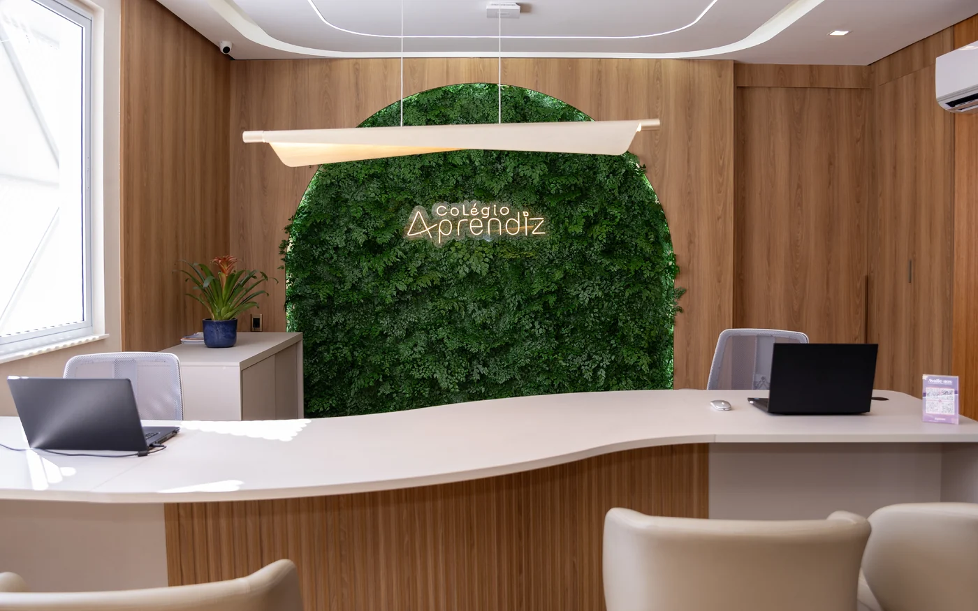 Recepção interna do Colégio Aprendiz com balcão de atendimento e parede verde